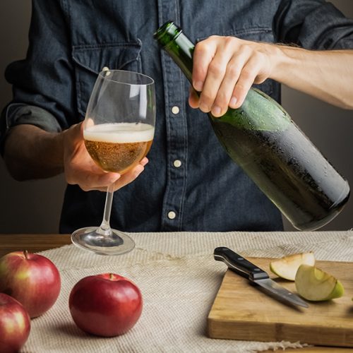 Male,Hands,Pouring,Premium,Cidre,In,Wine,Glass,Above,Rustic